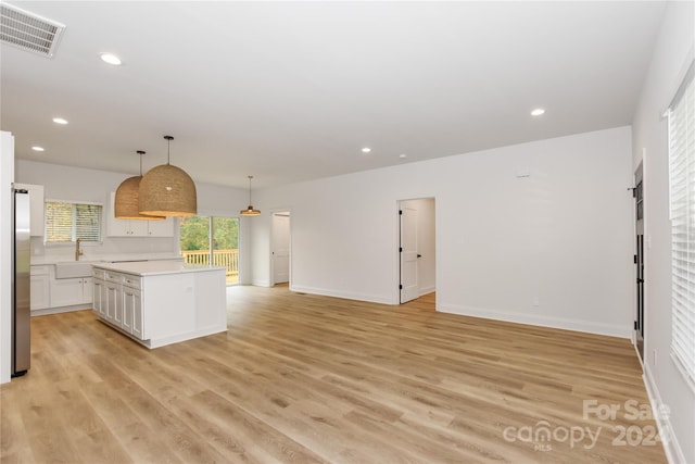 kitchen featuring white cabinets, a center island, light hardwood / wood-style floors, and hanging light fixtures