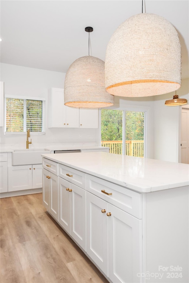 kitchen featuring white cabinets, decorative light fixtures, a healthy amount of sunlight, and light hardwood / wood-style flooring