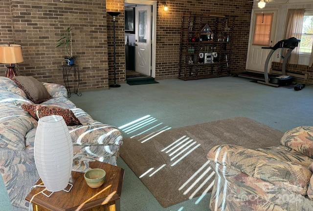 carpeted living room featuring brick wall