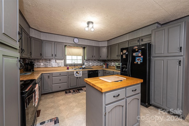 kitchen featuring black appliances, a textured ceiling, gray cabinets, butcher block countertops, and decorative backsplash