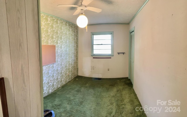 empty room featuring a textured ceiling, ornamental molding, carpet floors, and ceiling fan