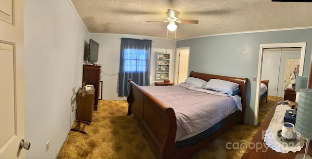 bedroom featuring dark colored carpet, ceiling fan, a textured ceiling, crown molding, and a closet