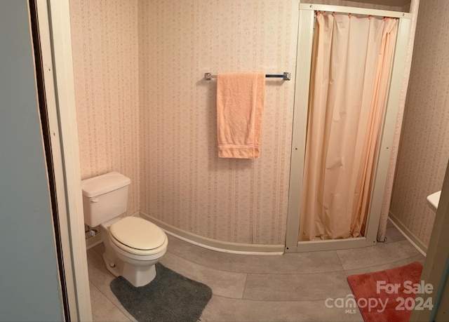 bathroom with a shower with shower curtain, tile patterned floors, and toilet