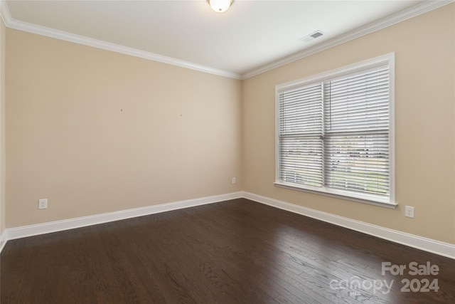 empty room with dark hardwood / wood-style floors and crown molding