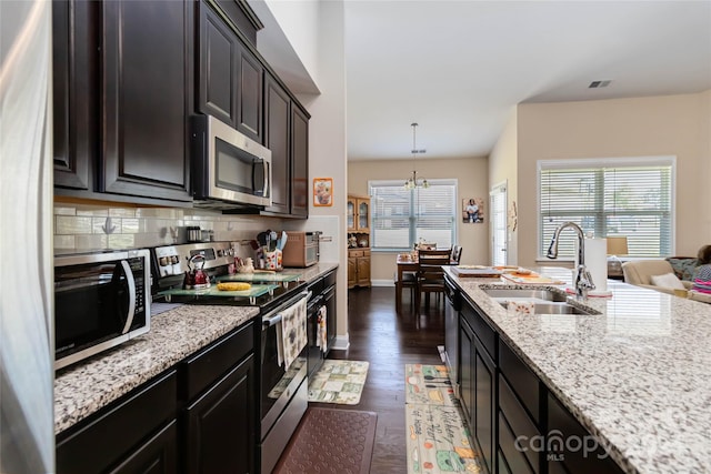 kitchen featuring stainless steel appliances, sink, tasteful backsplash, decorative light fixtures, and dark hardwood / wood-style flooring