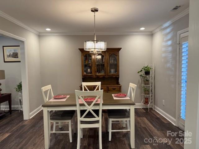 dining space with dark hardwood / wood-style flooring, an inviting chandelier, and crown molding