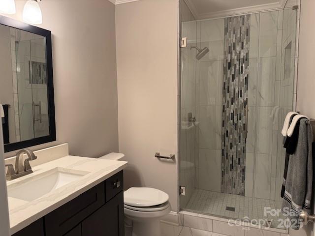 bathroom featuring a shower with shower door, ornamental molding, toilet, tile patterned floors, and vanity