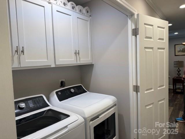 laundry room featuring ornamental molding, cabinets, and washing machine and clothes dryer