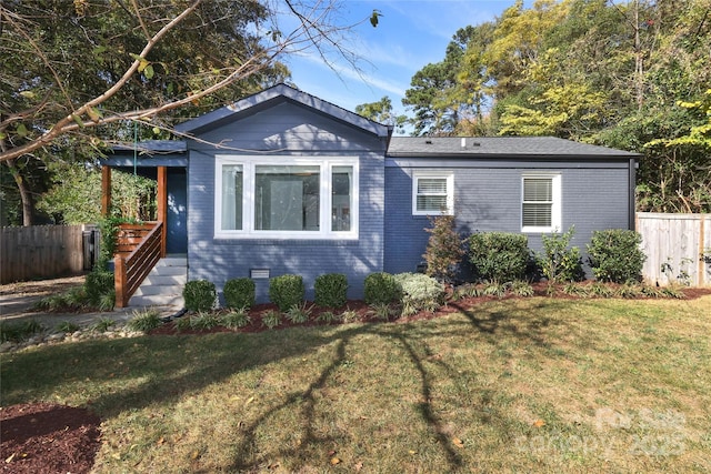 view of front of property featuring brick siding, fence, and a front yard