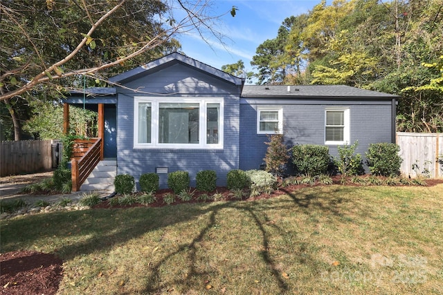 view of front of property with a front yard, brick siding, and fence