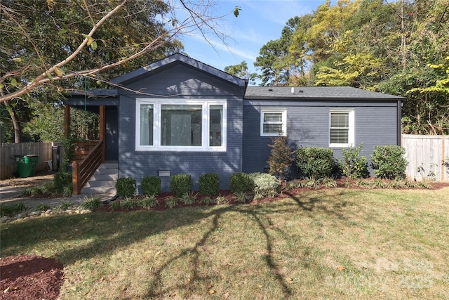 view of front of home with entry steps, a front yard, fence, and brick siding