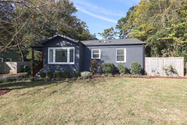 view of front of property featuring fence, a front lawn, and brick siding