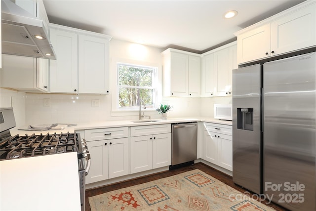 kitchen featuring appliances with stainless steel finishes, light countertops, under cabinet range hood, white cabinetry, and a sink