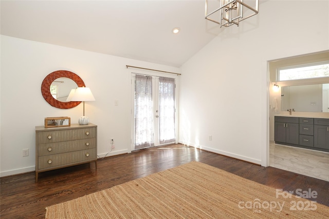 interior space with baseboards, lofted ceiling, dark wood-style flooring, an inviting chandelier, and a sink