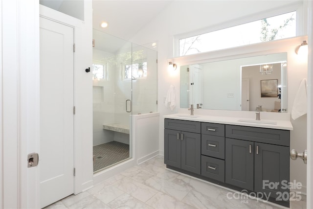 bathroom featuring marble finish floor, vaulted ceiling, a sink, and a stall shower