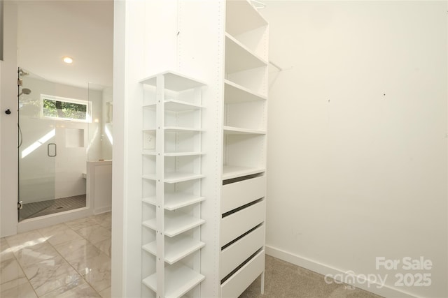 walk in closet featuring marble finish floor