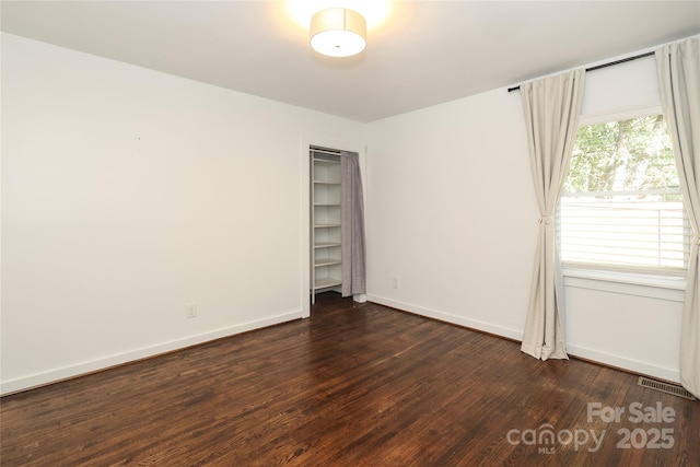 spare room with visible vents, dark wood finished floors, and baseboards