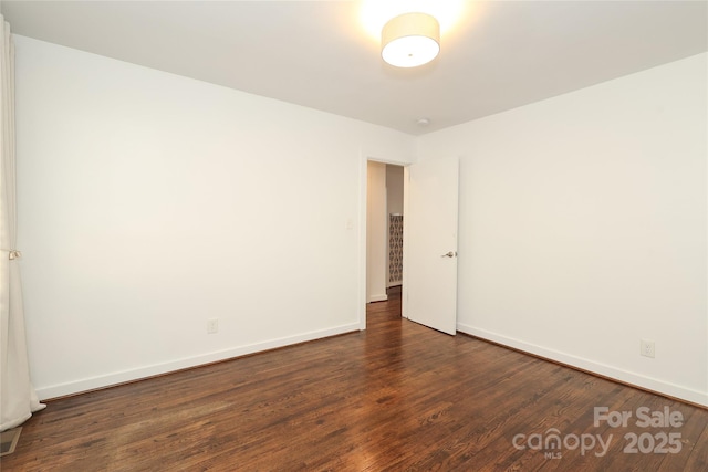 unfurnished room featuring baseboards and dark wood-style flooring