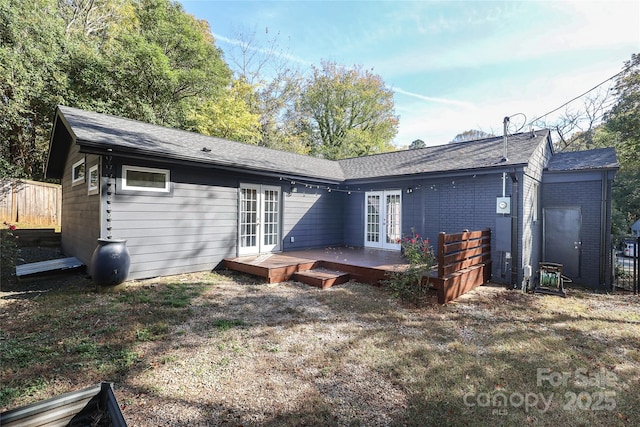 back of property with brick siding, a wooden deck, fence, and french doors