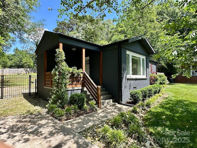 view of front of home with fence, a porch, brick siding, and a front yard