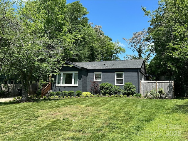 single story home featuring brick siding, fence, and a front yard