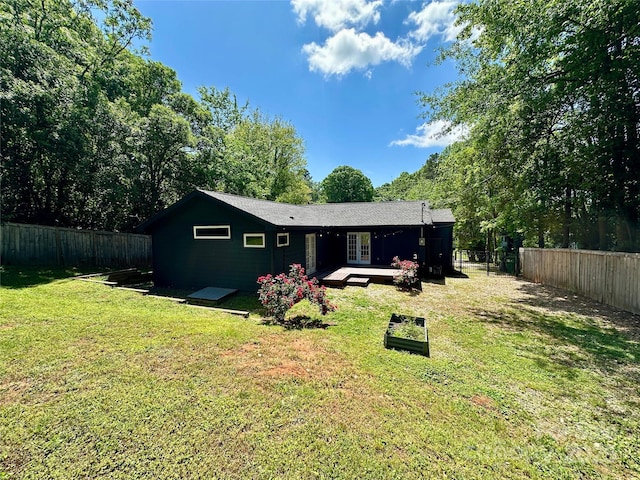rear view of property featuring a fenced backyard, a yard, and french doors