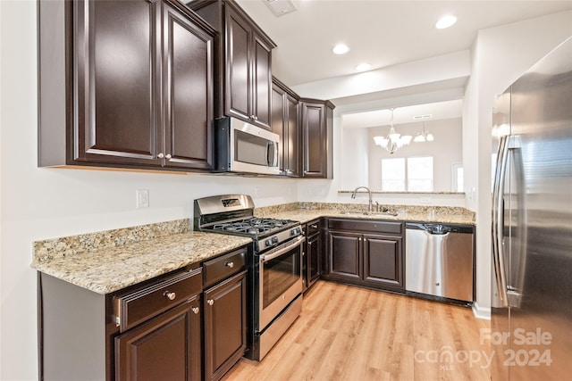 kitchen with stainless steel appliances, light hardwood / wood-style floors, hanging light fixtures, a chandelier, and sink