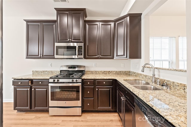 kitchen with stainless steel appliances, sink, light hardwood / wood-style flooring, and dark brown cabinetry