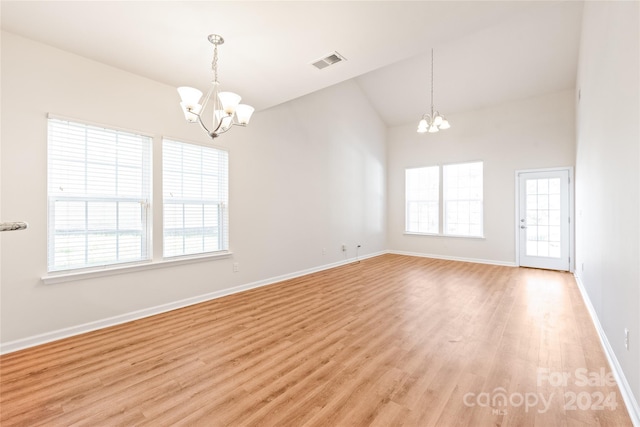 empty room with light hardwood / wood-style floors, an inviting chandelier, and lofted ceiling