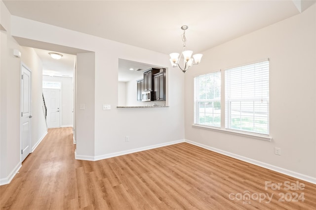 unfurnished dining area featuring light hardwood / wood-style floors and a chandelier