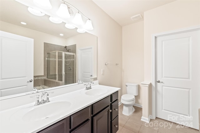 bathroom with toilet, vanity, tile patterned flooring, and a shower with shower door