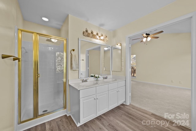 bathroom with hardwood / wood-style floors, ceiling fan, a shower with door, and vanity