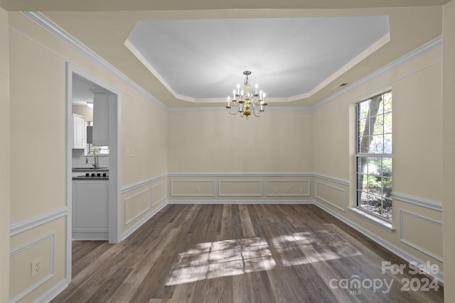 unfurnished dining area with dark hardwood / wood-style flooring, a raised ceiling, crown molding, sink, and an inviting chandelier