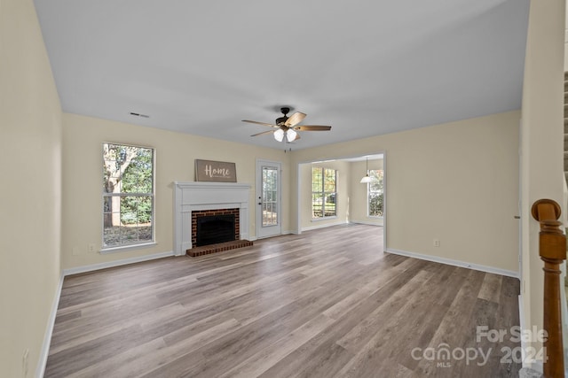 unfurnished living room with ceiling fan, light hardwood / wood-style floors, and a fireplace