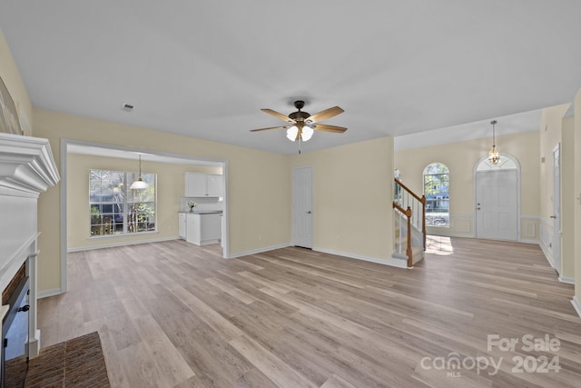 unfurnished living room featuring plenty of natural light, ceiling fan, and light wood-type flooring