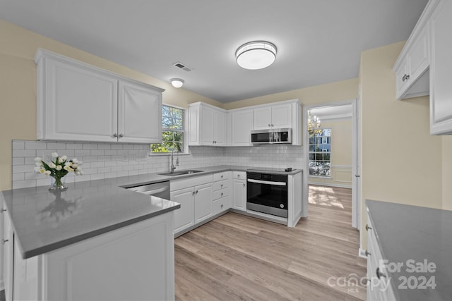 kitchen with a wealth of natural light, white cabinetry, sink, and appliances with stainless steel finishes