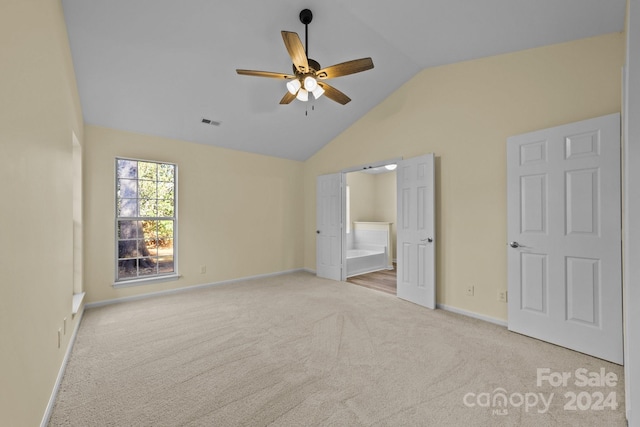 unfurnished bedroom featuring light carpet, ensuite bath, ceiling fan, and lofted ceiling