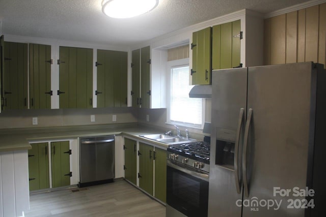 kitchen featuring stainless steel appliances, green cabinets, sink, a textured ceiling, and light wood-type flooring