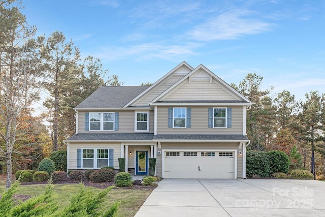 craftsman-style house with an attached garage, a shingled roof, and driveway