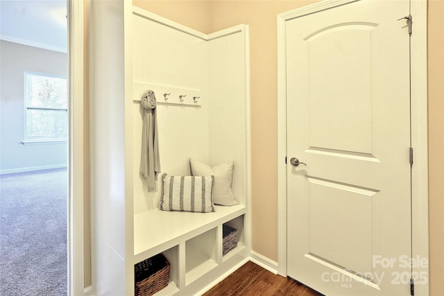 mudroom with crown molding, baseboards, dark colored carpet, and dark wood finished floors