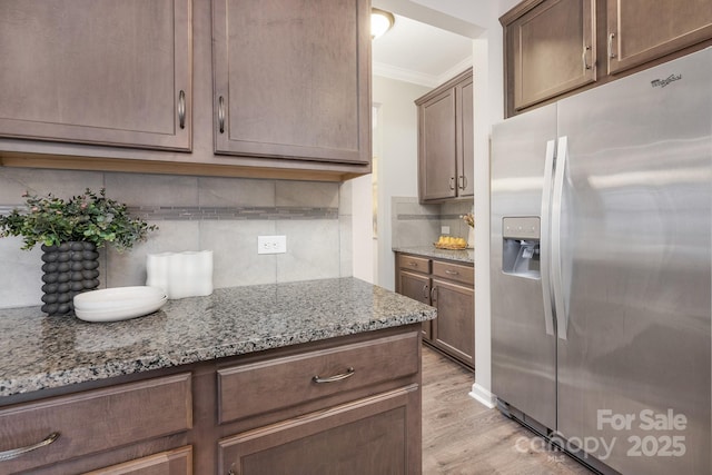 kitchen with light wood-style floors, ornamental molding, light stone countertops, and stainless steel refrigerator with ice dispenser