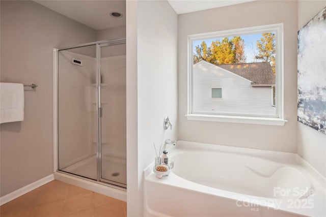 bathroom featuring a bath, a shower stall, tile patterned flooring, and baseboards