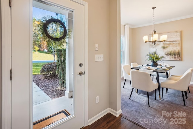 foyer entrance featuring ornamental molding, baseboards, a notable chandelier, and dark wood finished floors