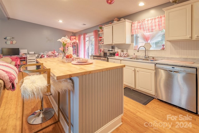 kitchen with sink, butcher block countertops, stainless steel dishwasher, a kitchen island, and light hardwood / wood-style flooring