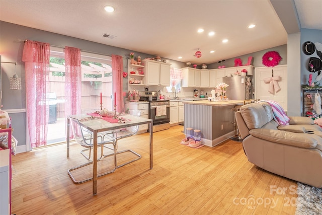 kitchen with stainless steel appliances, white cabinets, light hardwood / wood-style flooring, and a center island