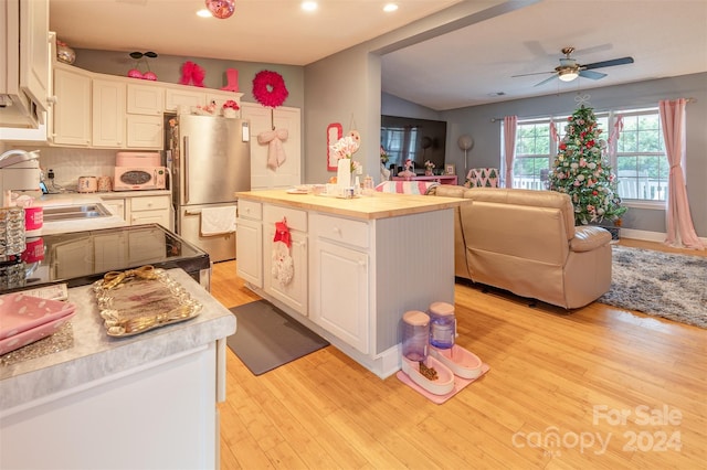 kitchen featuring white cabinetry, light hardwood / wood-style floors, a center island, and stainless steel refrigerator