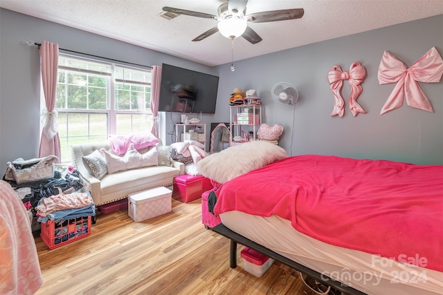 bedroom with hardwood / wood-style flooring, a textured ceiling, and ceiling fan