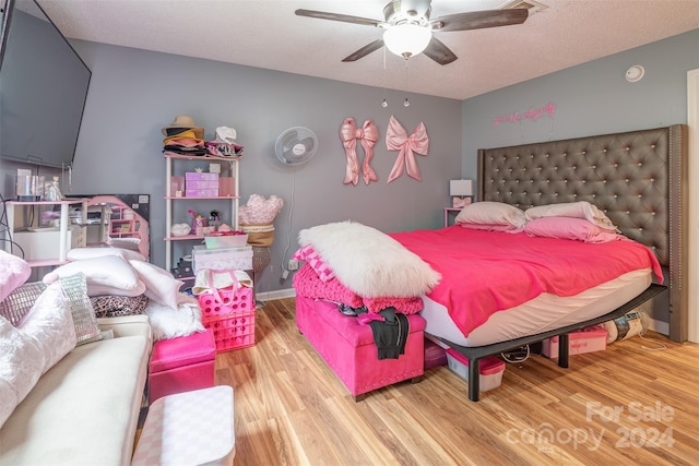 bedroom with ceiling fan, wood-type flooring, and a textured ceiling