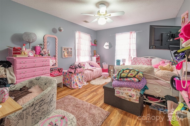 bedroom with a textured ceiling, wood-type flooring, and ceiling fan