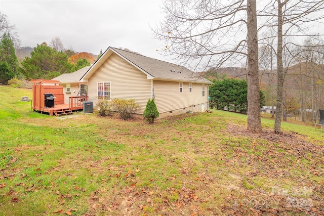 back of house featuring central AC unit, a wooden deck, and a yard